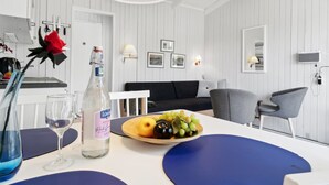 A modern, white-themed room with a dining area, a black sofa, and a grey chair. - "Kjera" - 200m from the sea by Interhome (Allinge)