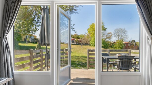 A room with a sliding glass door leading to an outdoor deck with a wooden fence and a table with chairs. - "Kjera" - 200m from the sea by Interhome (Allinge)