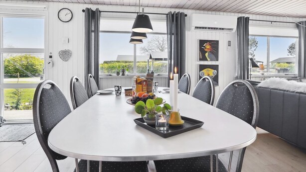 A dining area with a white table, black chairs, a candle, and a tray with fruits and a plant. - "Anisa" - 400m from the sea by Interhome (Haderslev)