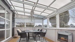 A sunroom with a glass ceiling, a fireplace, and a dining table with chairs. - "Anisa" - 400m from the sea by Interhome (Haderslev)