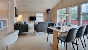 Un interno accogliente di una baita, con arredamento in legno, una zona pranzo e un televisore.