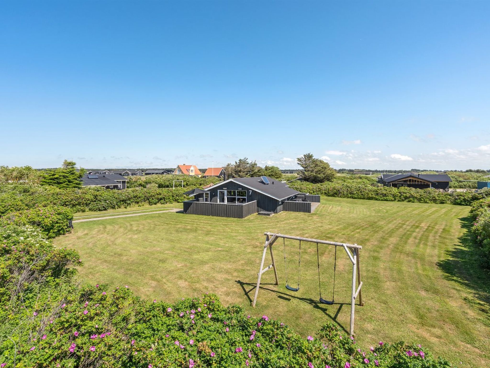 A residential area with houses, a grassy lawn, and a swing set.