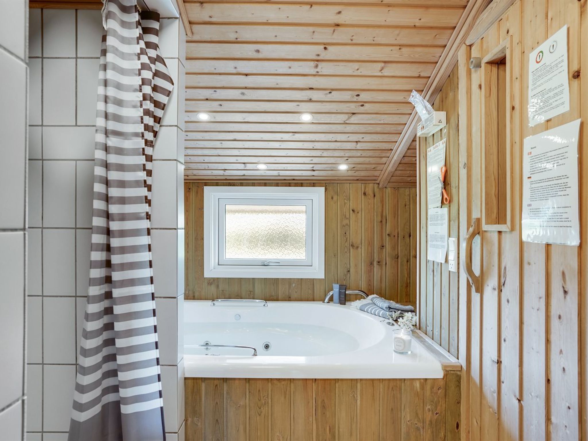 Une salle de bain moderne avec un intérieur en bois, une grande baignoire, une fenêtre et divers équipements.