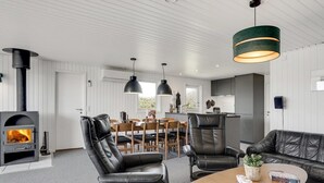 Un salon moderne avec une cheminée, des fauteuils en cuir, une table basse en bois et des luminaires suspendus.