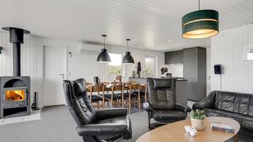 En moderne stue med pejs, læderstole, et træsofabord og hængende lamper.