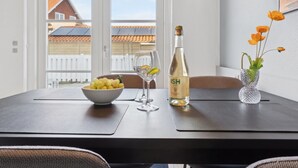 A dining table with a bottle of wine, a bowl of grapes, and a vase with flowers.