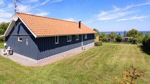 Ett tvåvåningshus med ett rött tegeltak, en satellitmottagare och en liten veranda med utemöbler.