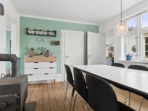 A modern kitchen with white cabinetry, a dining table with chairs, and a hanging light fixture.