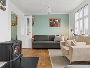A cozy living room with a fireplace, a sofa, a chair, and artwork on the walls.