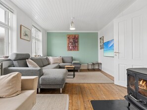 A living room with a sofa, a coffee table, a fireplace, and artwork on the walls.