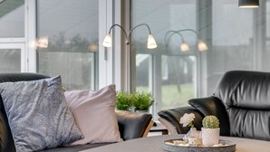 Ein modernes Wohnzimmer mit einem runden Couchtisch, Ledersofas und einem Fenster mit Blick ins Freie.