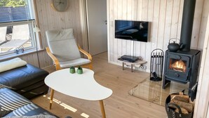 Un salon chaleureux avec un canapé, un fauteuil, un téléviseur et un poêle à bois.
