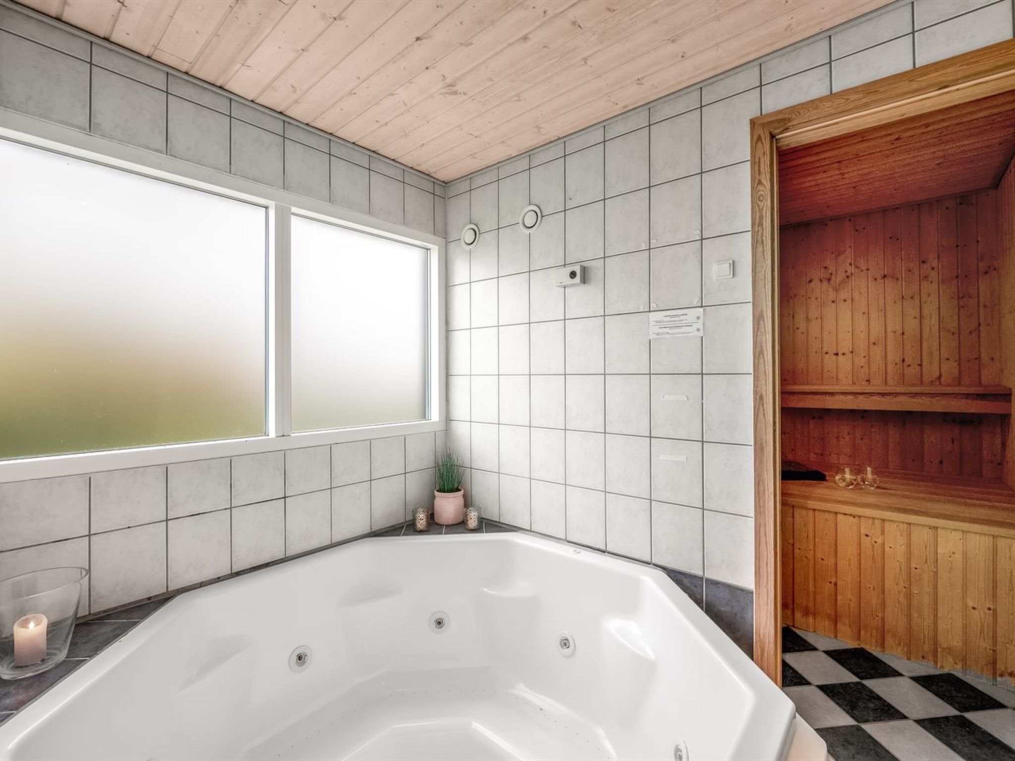 Ein Badezimmer mit einer großen Badewanne, einer hölzernen Sauna und einem Fenster.