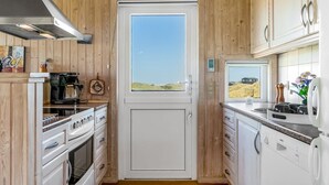 Een kleine keuken met houten lambrisering, een fornuis, oven en koffiezetapparaat.