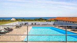 Une piscine avec des chaises longues et vue sur la mer.