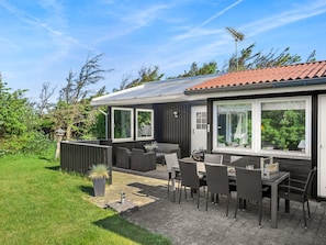 Une maison dotée d’un patio, de mobilier d’extérieur et offrant une vue sur la verdure environnante.