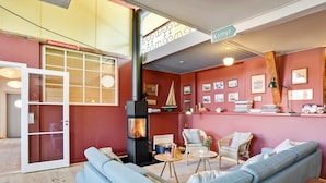 Ein gemütliches Wohnzimmer mit Kamin, einer Couch und einem Couchtisch. An der Wand hängen gerahmte Bilder und über dem Kamin befindet sich ein Schild mit der Aufschrift "Komyr".