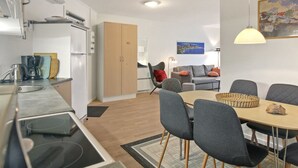 Ett modernt kök med en matplats, inklusive ett bord med stolar, en soffa och en lampa.