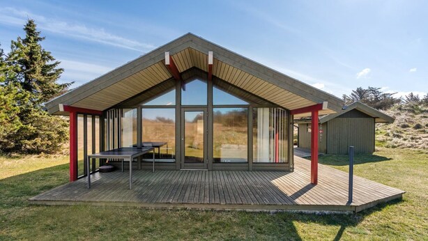 A modern house with a large glass window, a wooden deck, and a red railing. - "Alfrik" - 900m from the sea by Interhome (Blokhus)