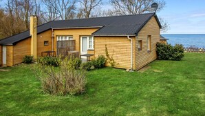 A wooden cabin with a black roof, a small porch, and a view of the sea. - "Zina" - 25m from the sea by Interhome (Gudhjem)