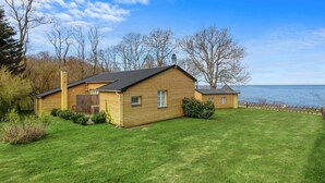 A two-story wooden house with a grassy yard and a view of the water. - "Zina" - 25m from the sea by Interhome (Gudhjem)