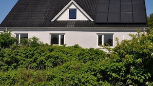 A house with a sloped roof, solar panels, and a small triangular window.