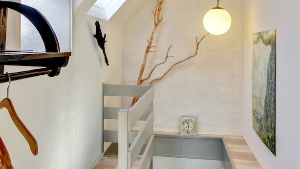 A modern interior with a skylight, a hanging light fixture, a staircase, and a wall-mounted clock.