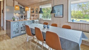 Ett modernt kök med träpanel, en matplats med ett bord i marmor och utsikt över omgivningen.