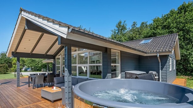 Eine moderne Außenterrasse mit Whirlpool, Sitzgelegenheit und überdachtem Patio.