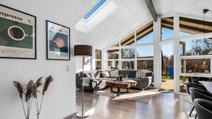 Ein geräumiges Wohnzimmer mit hohen Decken, großen Fenstern und modernem Design.