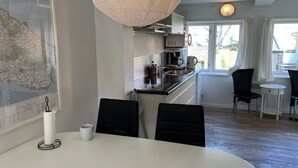 A modern kitchen with a dining area, featuring a large map on the wall, a hanging light fixture, and a view of the outdoors through the windows. - "Thyrne" - 500m from the sea by Interhome (Gudhjem)