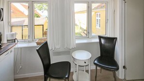 A small kitchen with two black chairs, a white stool, and a window with curtains. - "Thyrne" - 500m from the sea by Interhome (Gudhjem)