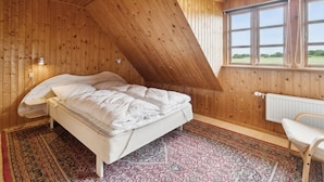 A bedroom with a sloped ceiling, a bed, a window, and a radiator. - "Helmer" - 3km from the sea by Interhome (Østermarie)