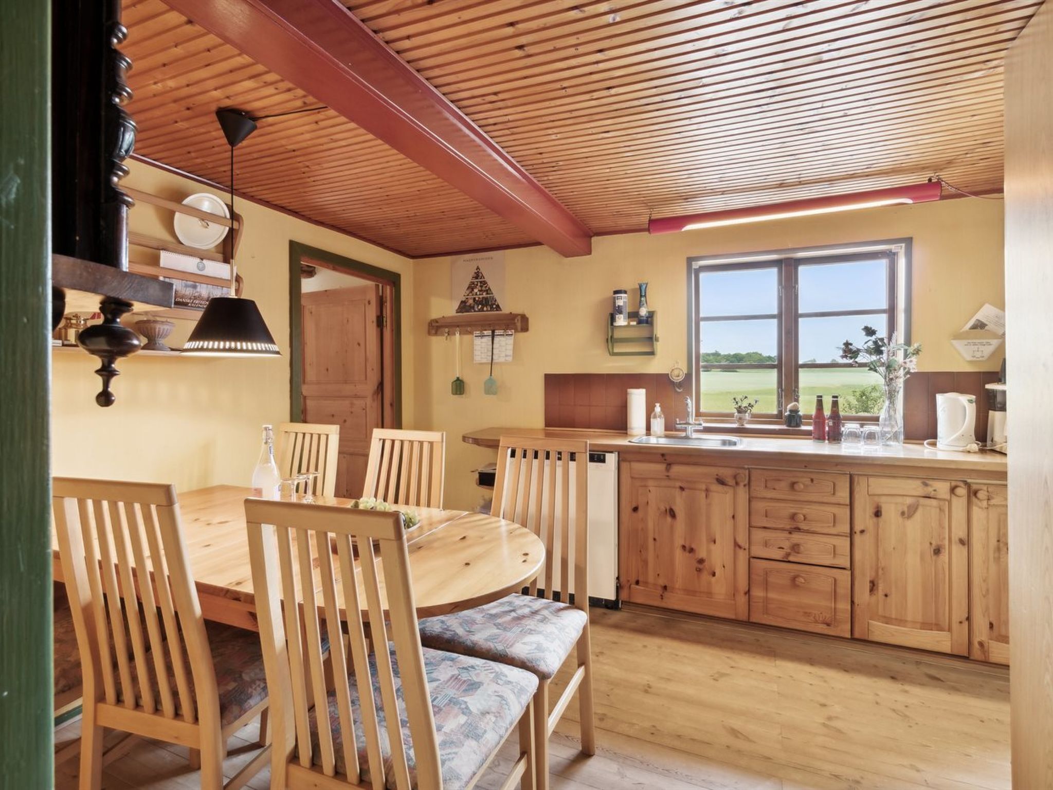 A cozy kitchen with wooden cabinets, a dining table with chairs, and a window offering a view of the outdoors.
