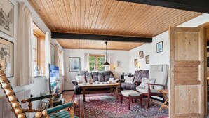 A cozy living room with a wooden ceiling, a large window, a sofa, a coffee table, and a rocking chair. - "Helmer" - 3km from the sea by Interhome (Østermarie)