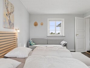Een slaapkamer met een bed, een sofa, een hoofdeinde, een raam en een deur.