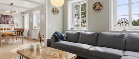 A modern living room with a grey sofa, a wooden coffee table, and a hanging light fixture.