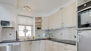 A modern kitchen with white cabinets, a black countertop, and a checkered floor pattern.