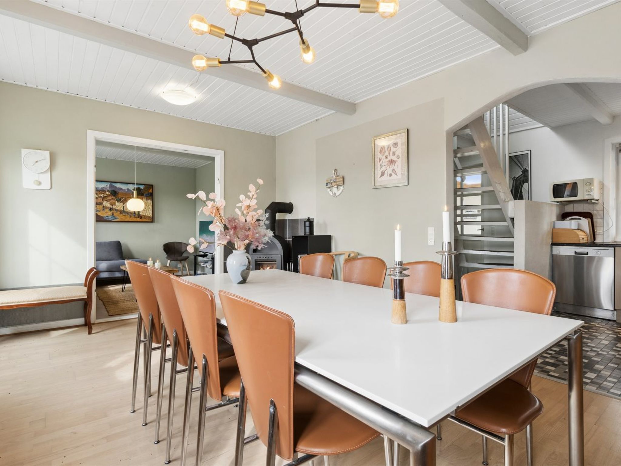 A spacious dining area with a long table, multiple chairs, and a modern chandelier.