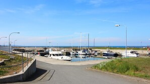 Ein Yachthafen mit vertäuten Booten, ein Betonweg, der zum Wasser führt, und ein klarer Himmel.