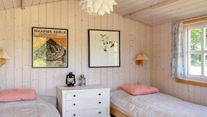 A cozy room with two beds, a white dresser, and a window with curtains.