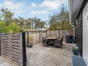 Une terrasse avec une table et des chaises, un barbecue et une clôture en bois.
