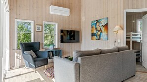 Un salon moderne avec un canapé gris, un fauteuil bleu et un téléviseur à écran plat fixé au mur.