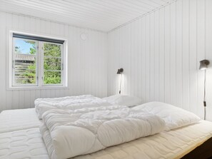 Une chambre à coucher avec un lit, une fenêtre et deux lampes fixées au mur.