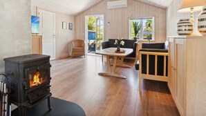 A cozy room with a wood-burning stove, a sofa, a dining table, and a lamp. - "Ilmari" - 150m from the sea by Interhome (Nexø)