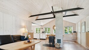 A spacious kitchen with wooden cabinets, a dining area with a wooden table and chairs, and a large window providing natural light. - "Ilmari" - 150m from the sea by Interhome (Nexø)