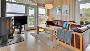 Una sala de estar moderna con chimenea, sofá y ventanas amplias.