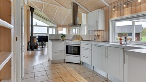 Una cocina moderna con armarios blancos, una estufa grande y un ventanal con vistas a un jardín.