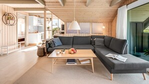 Ein modernes Wohnzimmer mit einer großen Eckcouch, einem Couchtisch und Blick ins Freie.