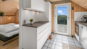 Eine kompakte Küche mit weißen Schränken, einer Arbeitsplatte und einer Tür zu einem Außenbereich.